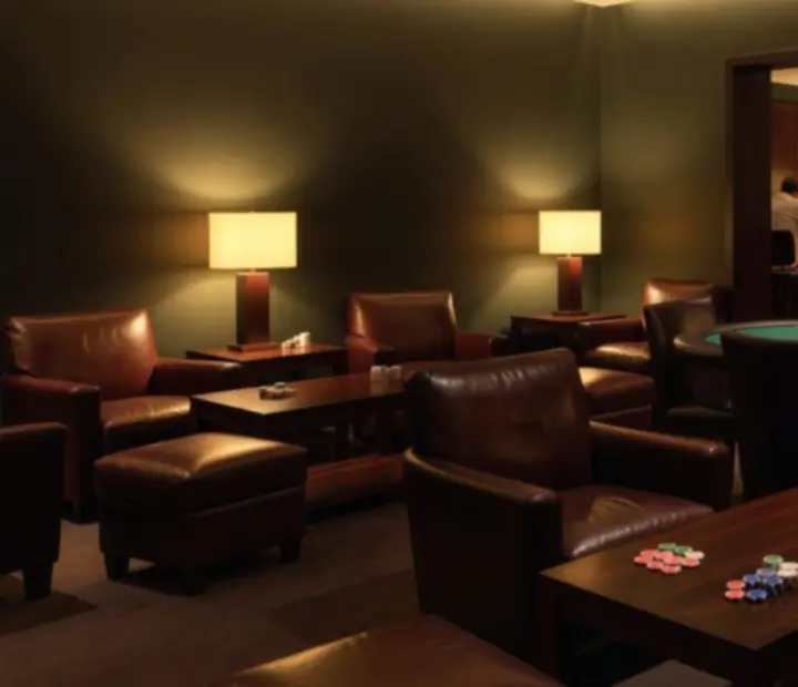 Dark olive card lounge at ADSIGHT LTD with poker tables, lounge seating and warm lighting.