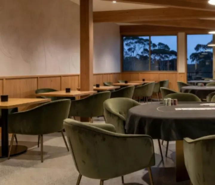 Card lounge with poker tables and soft olive seating at ADSIGHT LTD