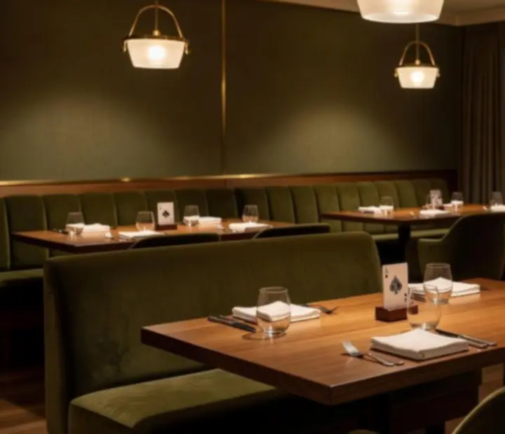 Evening restaurant dining room with timber tables, olive seating and soft lighting
