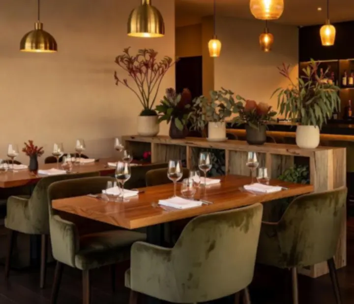 Warm Australian dining room and card lounge at ADSIGHT LTD with timber tables, olive seating and a poker table set for the evening.